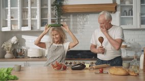 Fun and joy in home kitchen, happy elderly married couple dancing by music. Medium portrait of joyful aged man and woman in cozy modern interior, feeling good and positive emotions, healthy old people - Powered by Shutterstock - Get 15% off with code: PIKWIZARD15