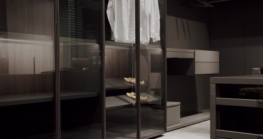 Dressing room with shirts. Elegant Wooden Built Walk In Closet Decoration. Luxury Dressing Room. Modern Sliding Doors. Black wardrobe with Sliding Black Doors. Luxury Bedroom With Walk In Closet.