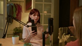 Teen girl sitting in front of her podcast guest, she speaking with energy and positive emotions. Girl holding black smartphone with opened script file - Powered by Shutterstock - Get 15% off with code: PIKWIZARD15