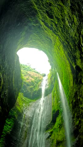 Interior view looking up at multiple streams of Madakaripura Waterfall through a cave-like opening, Java, Indonesia.