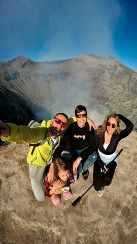 Family takes a selfie high above the steaming crater of Bromo volcano, Indonesia.