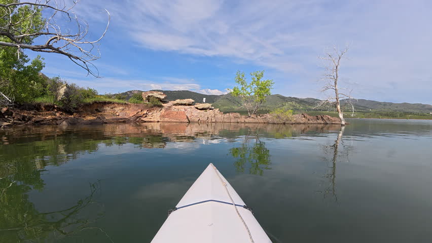 First person POV from springtime paddling a kayak or canoe on Horsetooth Reservoir in foothills of Rocky Mountains in Colorado