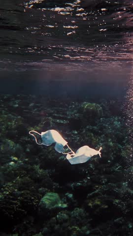 Garbage in the sea. medical mask at sea. used medical masks are slowly drifting underwater in the sun lights. Backlighting. garbage environmental pollution problem