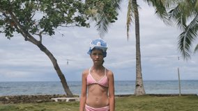 Young girl wearing a pink swimsuit giving a thumbs upafter putting on snorkel mask, surrounded by a stunning ocean view and swaying palm trees, slow motion. Summer vacation concept - Powered by Shutterstock - Get 15% off with code: PIKWIZARD15