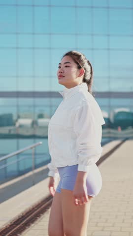 Young asian athlete walking in slow motion near modern building