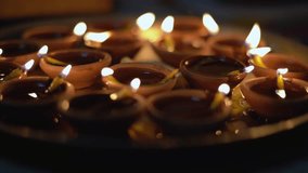 Macro shot showing plate filled with clay diya lamps filled with oil and with a flaming cotton wick showing the sanctity of fire in hindu religion during diwali - Powered by Shutterstock - Get 15% off with code: PIKWIZARD15