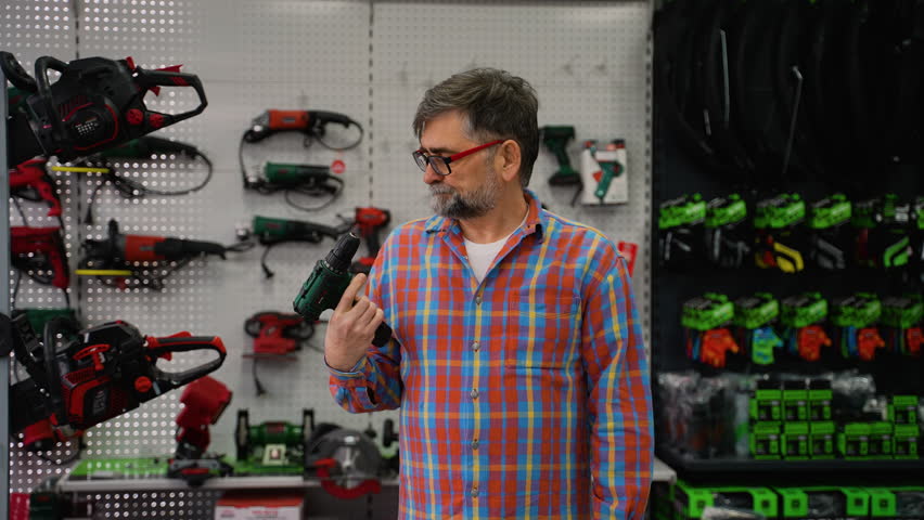 Senior Man Choosing Cordless Drill in Hardware Store
