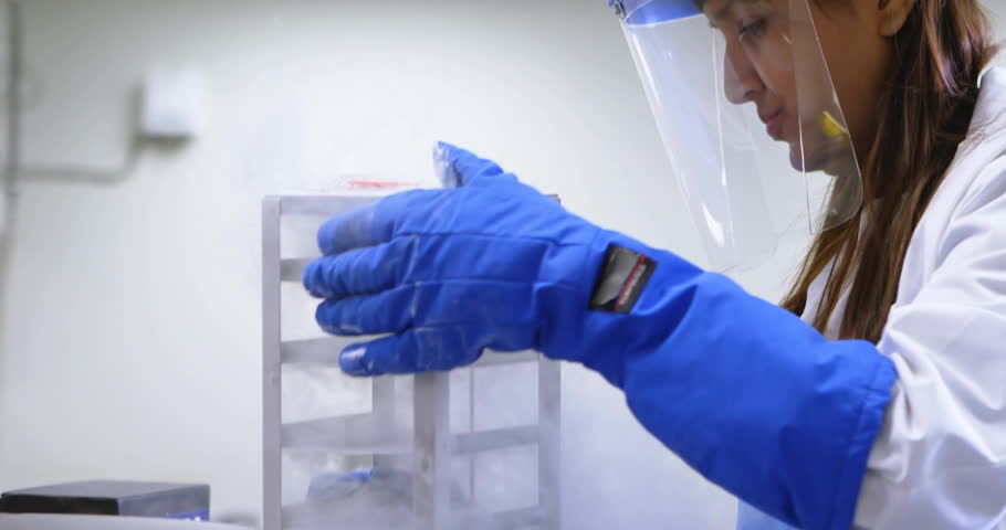 Lab scientist positioning gloves on dewar lifting rack aligning samples overlaying graph on shield. Cryogenics, biotechnology, precision, innovation, scientific, technology, research