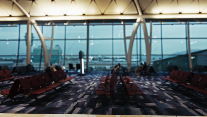 Spacious interior of Hong Kong airport terminal showcasing passenger seating. Large windows offer views of the runway, accented by modern architectural elements. Soft lighting enhances the traveler
