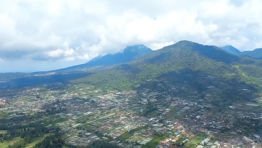 Video from above in the form of houses, trees, clouds and hills
