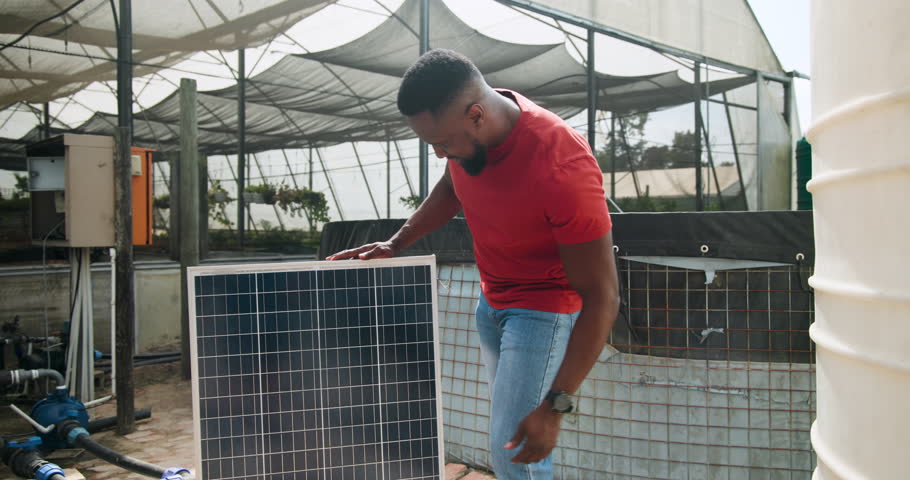 Man in red shirt installing solar panel at greenhouse, focusing on renewable energy. installation, solar power, technology, sustainability, electrician, innovation