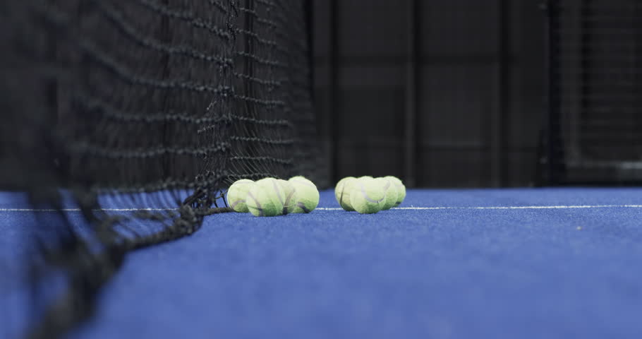 Spotting tennis balls, male padel player scooping them with black racket on blue turf, copy space. Sports, activity, athletic, teamwork, motion, recreational, fitness