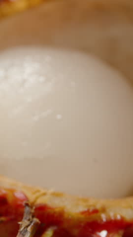 Dolly Slider Close Up of Hand Holding Rambutan Seed After Eating Flesh with Empty Fruit Shells in Background on Reflective Surface Under Studio Lighting.