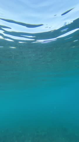 Slow motion shot of powerful blue wave in transparent tropical water of Indian Ocean. No people seascape at hot sunny day. Low angle shot. Wide angle underwater footage. 4k vertical video
