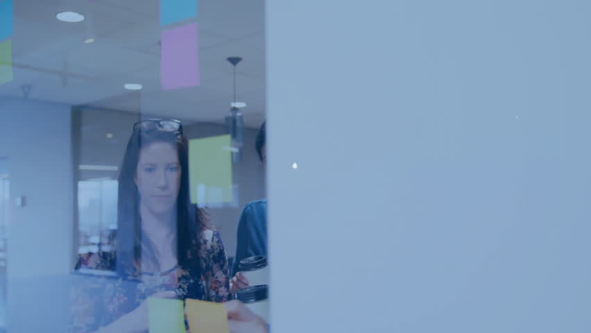 Employees studying sticky notes in business meeting sparking overlay of globe and chart icons. Collaboration, innovation, teamwork, data visualization, digital connectivity, modern workspace, - Powered by Shutterstock - Get 15% off with code: PIKWIZARD15