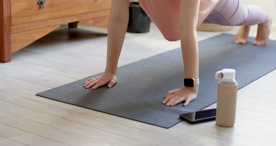 Settling into plank on black mat, Asian female doing knee tuck and forearm plank at home. Fitness, workout, balance, strength, yoga, wellness, home fitness