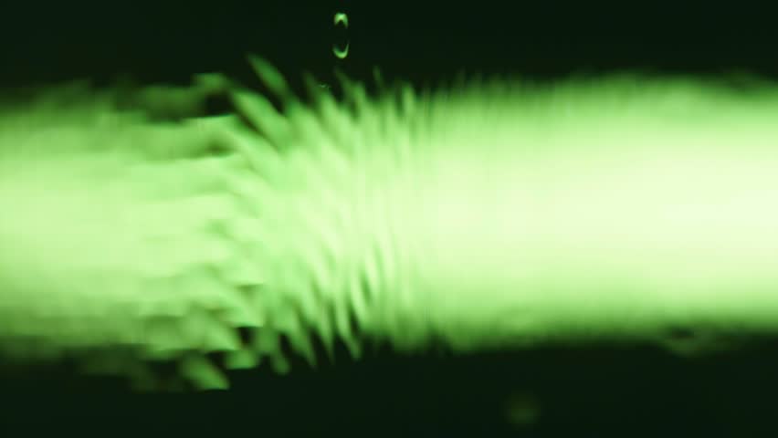 Macro super slow motion close up 1000 fps dynamic vertical video. Wave surface vibration oil liquid in green color. Create pulse wave in dark black green background. Purity clean water vibrant effect