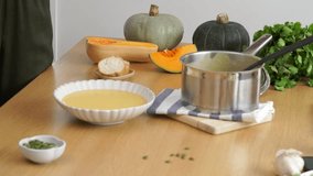 Adding pumpkin seeds to hot creamy Pumpkin Soup on the wooden table  - Powered by Shutterstock - Get 15% off with code: PIKWIZARD15
