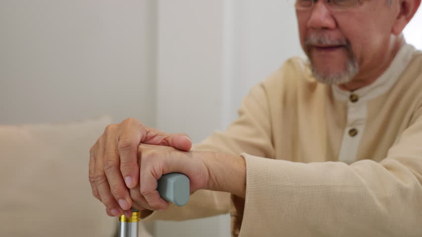 Close up hands of doctor or nurse assisting holding hand of old man patient on cane or walking stick during a medical checkup, doctor palm covering hand of senior, Health care and medical elderly care