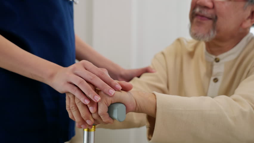 Close up hands of doctor or nurse assisting holding hand of old man patient on cane or walking stick during a medical checkup, doctor palm covering hand of senior, Health care and medical elderly care