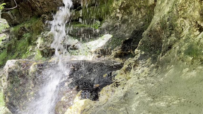 Handheld half speed clip of a small waterfall in South Carolina in dappled sunlight