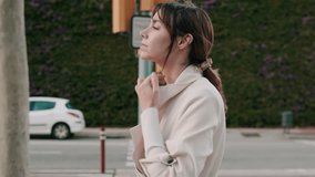 Young woman in stylish trench coat walks down a city street, pausing at a crosswalk as she adjusts her collar. She reflects, appearing thoughtful and confident. - Powered by Shutterstock - Get 15% off with code: PIKWIZARD15