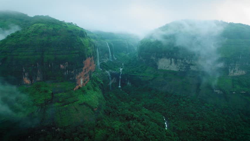 4K Aerial view of Dramatic monsoon clouds on Sahyadri hills. Devkund waterfall as seen from Savlya ghat view point. Rainy days landscape in Maharashtra, India. Waterfall flowing in mountain after rain