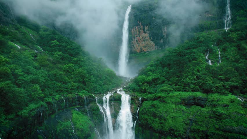 4K Aerial shot of mesmerising Nanemachi waterfall falling from cliff in Sahyadri hills during monsoon season at Maharashtra, India. Drone view of powerful waterfall in lush green forest landscape. 