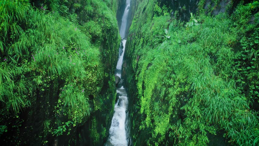 4K Aerial shot of Saatsada waterfall flowing in narrow valley of Sahyadri Hills in Maharashtra, India. Waterfall flowing between two mountain creek during monsoon. Scenic nature view.