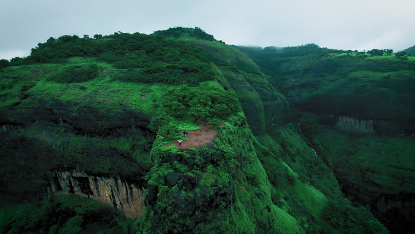 4K Aerial shot of Lush green landscape as seen from Savalya Ghat view point in Tamhini Ghat near Pune in Maharashtra, India. Rotating drone shot of Sahyadri hills during rainy day. Nature background