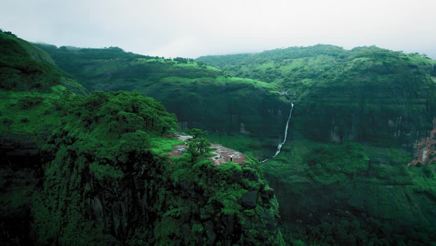 4K Aerial shot of Lush green monsoon landscape and Ring waterfall as seen from Savalya Ghat view point in Maharashtra, India. Rotating drone shot of Sahyadri hills during rainy day. Travel background - Powered by Shutterstock - Get 15% off with code: PIKWIZARD15