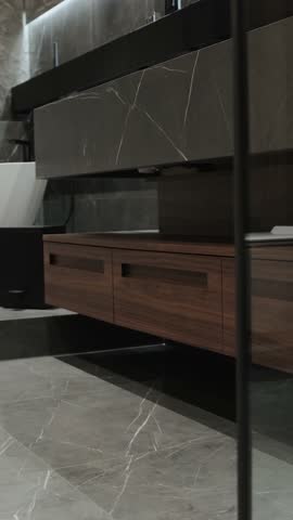 Vertical screen: Marble sink with beautifully crafted wooden base and drawers in a dark bathroom