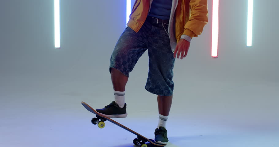 Minimal studio neon tubes activating, man stepping onto skateboard, lifting and inspecting deck. Urban, dynamic, vibrant, sport, youth, energy, nightlife