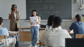 Asian female student reading project presentation to classmates and teacher at High School - Powered by Shutterstock - Get 15% off with code: PIKWIZARD15