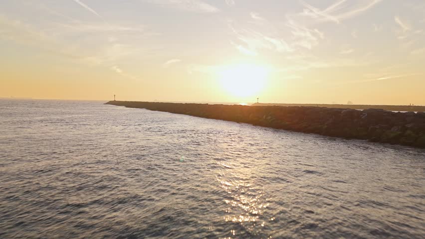 Aerial flyover of jetties at Seal Beach, California at golden hour with San Gabriel River and Alamitos Bay Inlet connecting with the Pacific Ocean