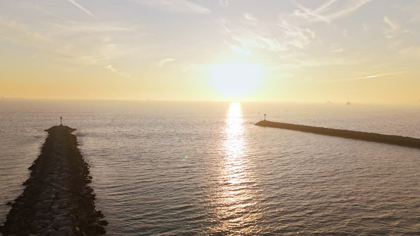 Aerial reveal of jetties at Seal Beach, California at golden hour with San Gabriel River connecting with the Pacific Ocean