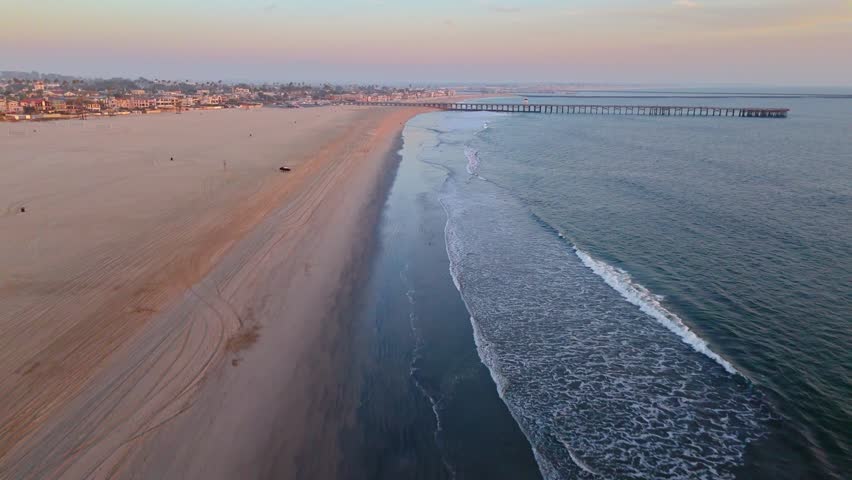 Aerial view of Seal Beach Municipal Pier at golden hour with waves washing onto the beach, Seal Beach, California
