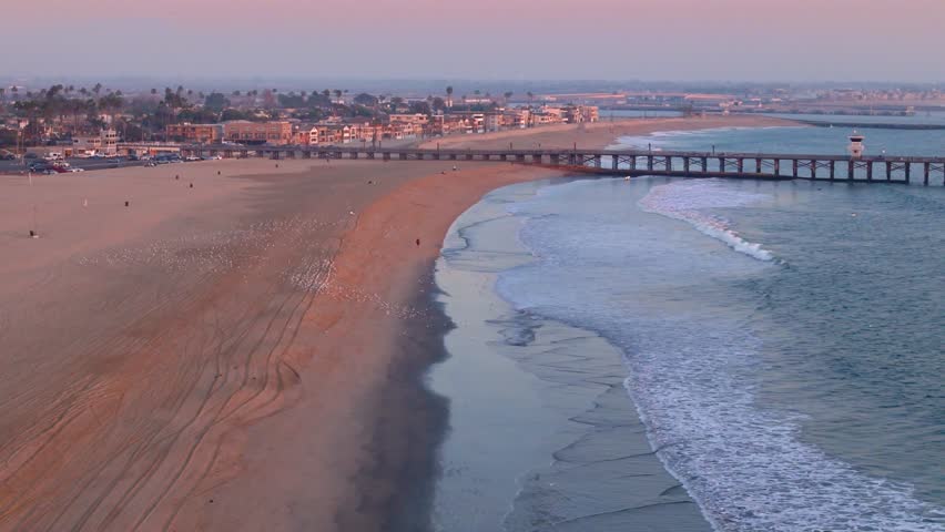 Aerial view of Seal Beach Municipal Pier at golden hour with waves washing onto the beach, Seal Beach, California