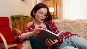 Young woman sits on home sofa, reading through old personal journal notebook and smiling with nostalgic mood. Girl reflects on memories with calm expression, embracing past thoughts and quiet emotion. - Powered by Shutterstock - Get 15% off with code: PIKWIZARD15