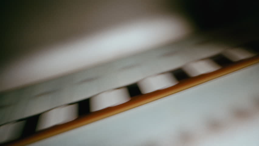A close-up view of a vintage movie projector film gate showing a film reel moving smoothly through the classic mechanical system