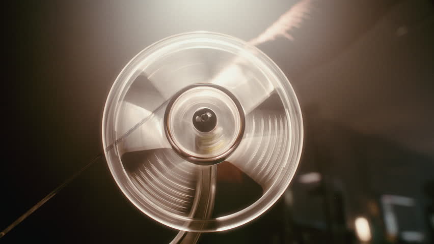 Close-up of manual film projection featuring a hand crank turning a rolling film reel on a vintage projector