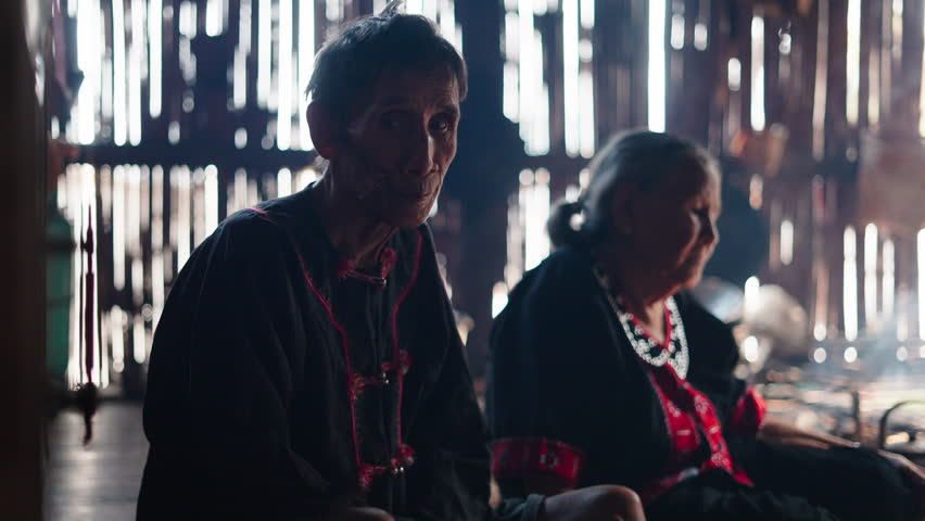 An elderly couple from the Lahu tribe in Thailand sitting together dressed in a traditional way