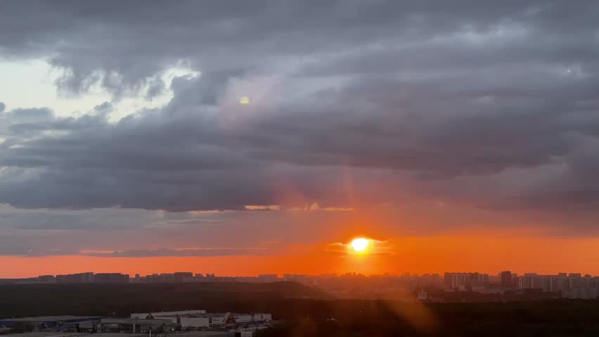 Time-lapse clouds race across a vibrant sunset sky, casting fleeting shadows on the city