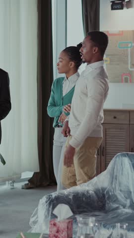 House on sale. Caucasian bearded adult rela estate agent showing new modern apartment home for african american young married couple.
