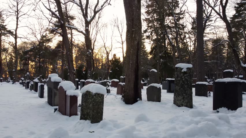 bunch of snow covered graves in a graveyard during the sunset