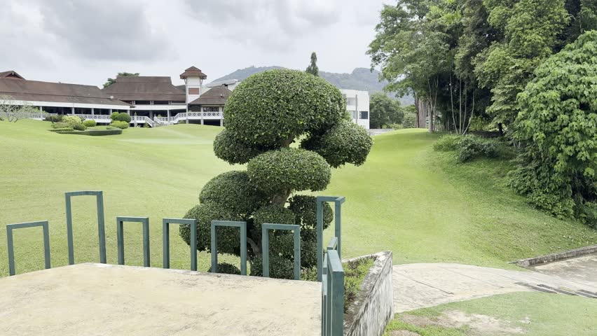 Tropical Luxury Golf Course with Palm Trees, Green Fairway, Water Features, Concrete Cart Paths, Distance Marker, Red Flag Hole. Modern Residential Buildings in Background. Play Signage. Hills View.