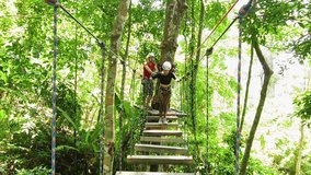 A man and a woman is walking across a challenging ropes course in the extreme park - Powered by Shutterstock - Get 15% off with code: PIKWIZARD15