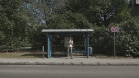 Man in Munich, Germany waits at bus stop, checking his watch. Public transport is delayed due to traffic, strike or breakdown, common urban commuting issues. Streik Verkehrsbetriebe in Deutschland.  - Powered by Shutterstock - Get 15% off with code: PIKWIZARD15