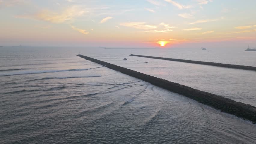 Aerial orbit of jetties at Seal Beach, California at sunset with San Gabriel River and Alamitos Bay Inlet connecting with the Pacific Ocean