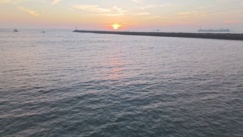 Aerial flyover of jetties at Seal Beach, California at sunset with San Gabriel River and Alamitos Bay Inlet connecting with the Pacific Ocean